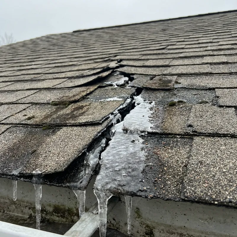 Damaged roof shingles with winter ice damage